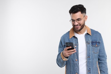 Photo of Happy young man using smartphone on white background, space for text