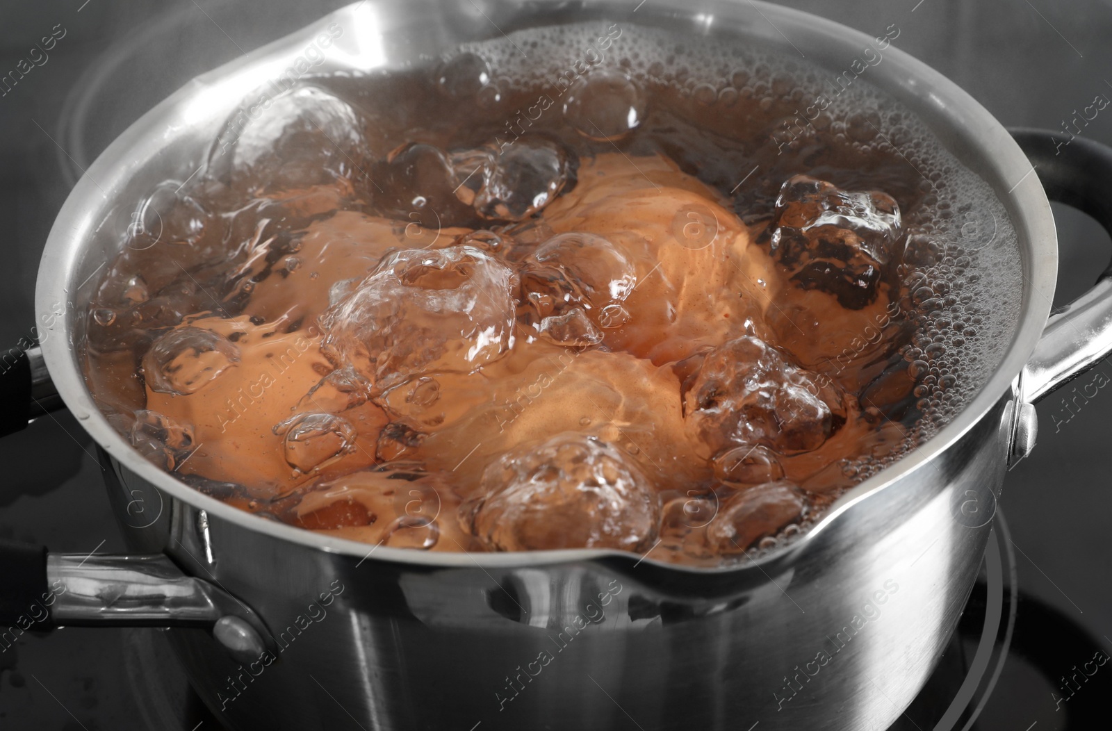 Photo of Cooking chicken eggs in pot on electric stove, closeup view