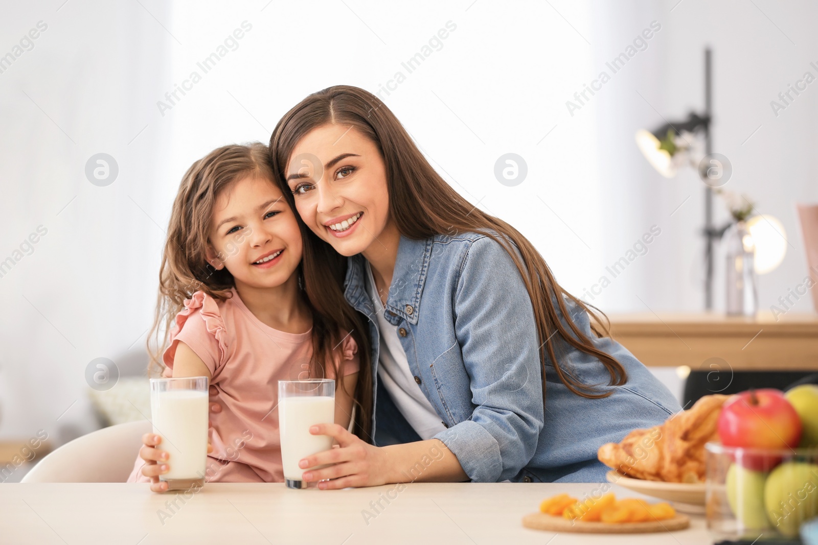 Photo of Mother and daughter having breakfast with milk at table