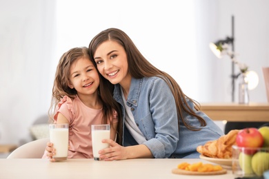 Photo of Mother and daughter having breakfast with milk at table