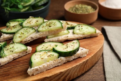 Photo of Tasty sandwiches with cream cheese and cucumber on wooden table, closeup