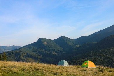 Picturesque mountain landscape with camping tents in morning