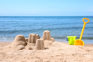 Photo of Little sand figures and plastic toys on beach near sea