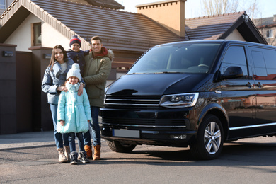Happy family with little children near modern car on street