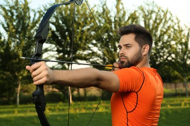 Photo of Man with bow and arrow practicing archery in park