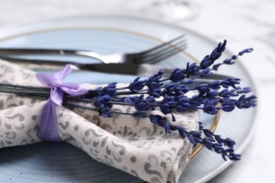 Photo of Cutlery, napkin, plates and preserved lavender flowers on table, closeup