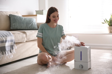 Woman near modern air humidifier at home