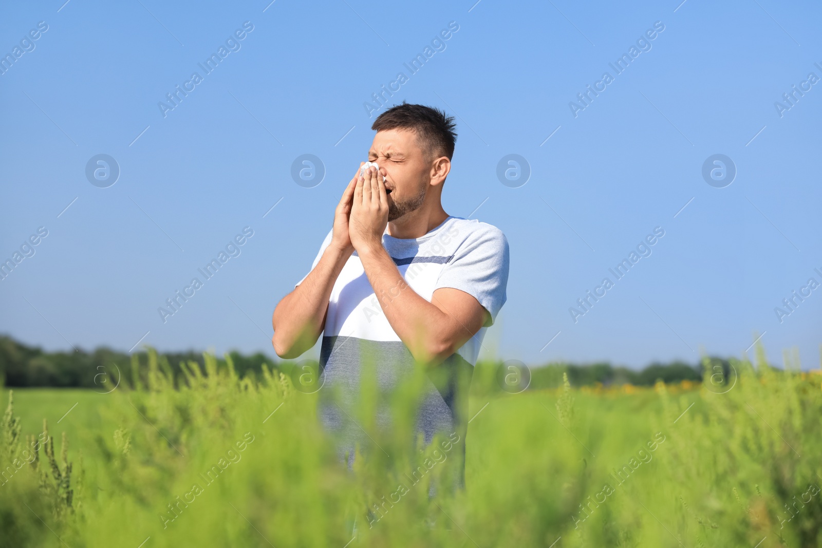 Photo of Man suffering from ragweed allergy outdoors on sunny day