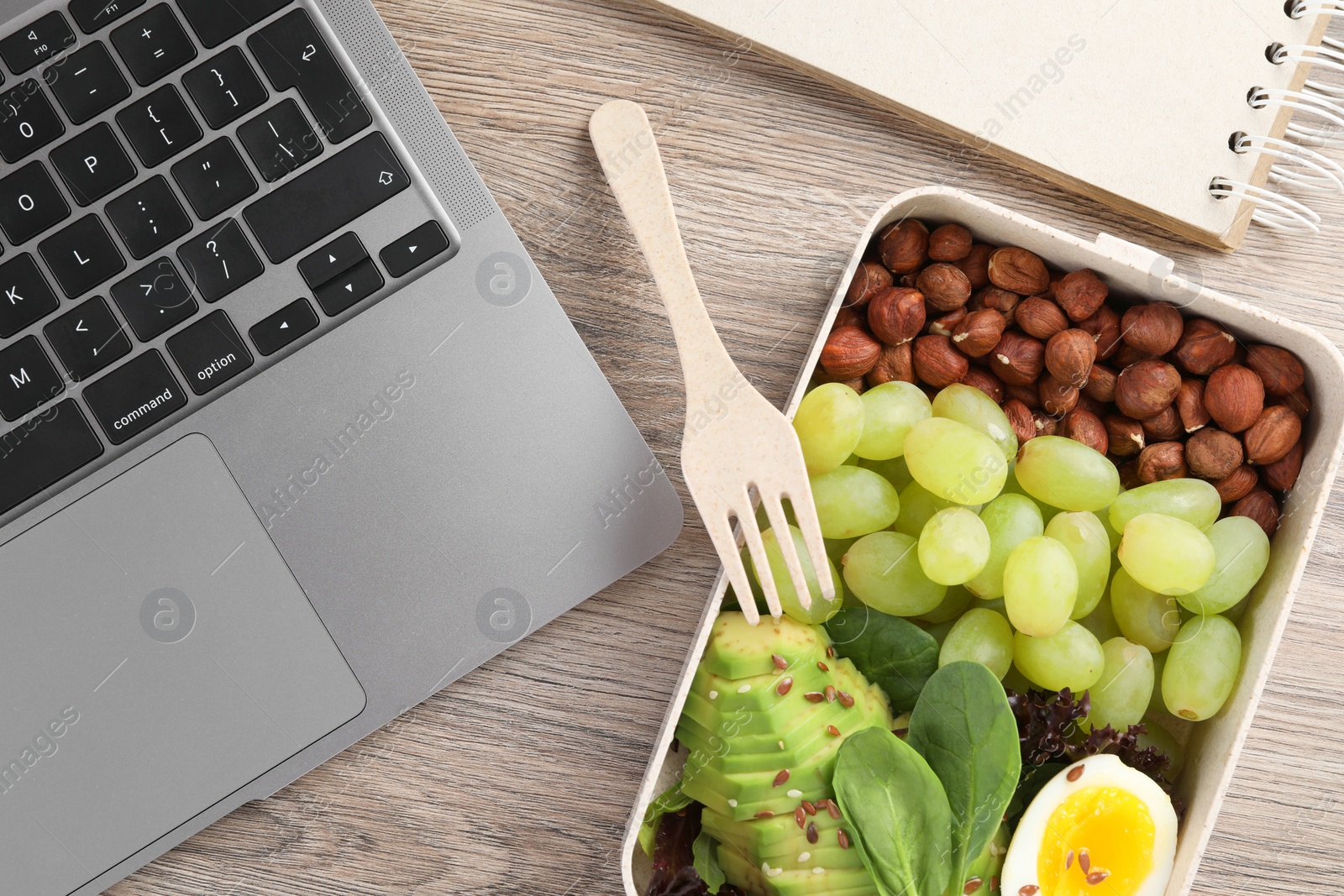 Photo of Healthy products high in vegetable fats near laptop on wooden table, flat lay