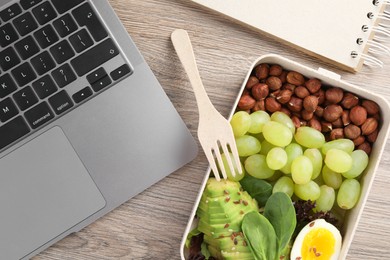 Photo of Healthy products high in vegetable fats near laptop on wooden table, flat lay