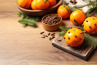 Photo of Delicious fresh tangerines with cloves on wooden table. Christmas celebration