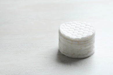 Stack of soft cotton pads on light background, space for text