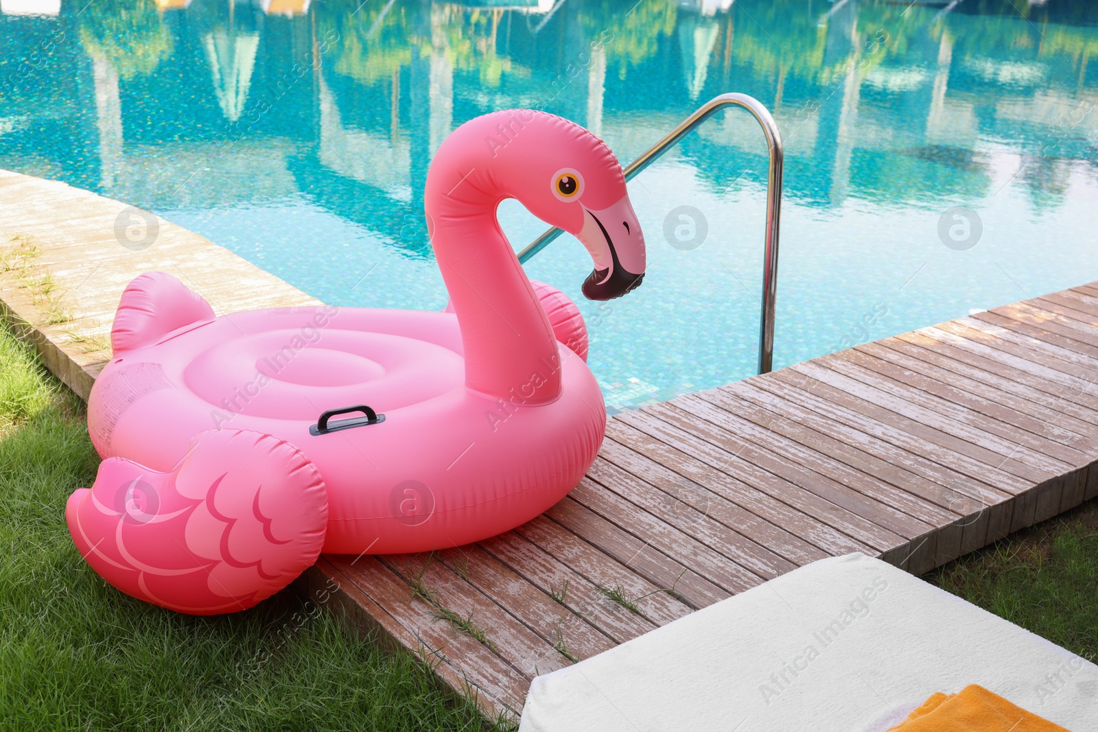 Photo of Float in shape of flamingo on wooden deck near swimming pool at luxury resort