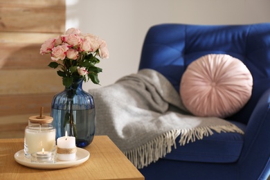 Vase with beautiful flowers and burning candles on wooden table indoors, space for text. Interior elements