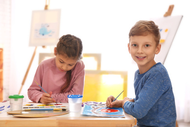 Photo of Cute little children painting at table in room