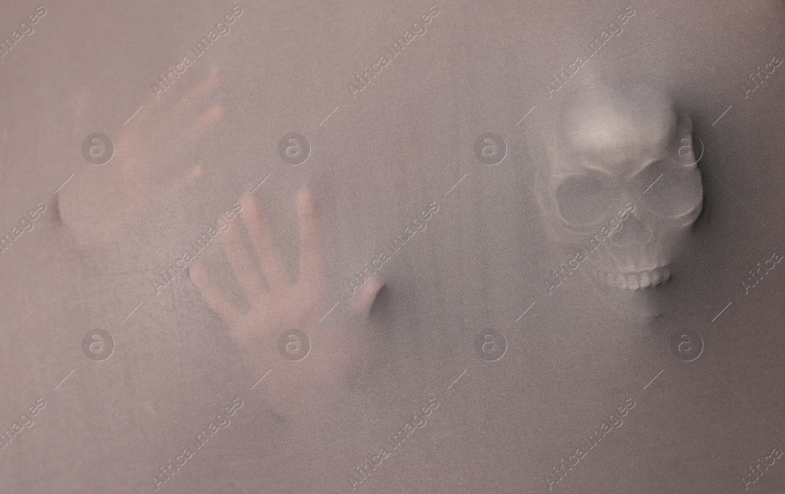 Photo of Silhouette of creepy ghost with skull behind grey cloth