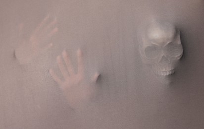 Photo of Silhouette of creepy ghost with skull behind grey cloth