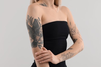 Photo of Woman with cool tattoos on light background, closeup