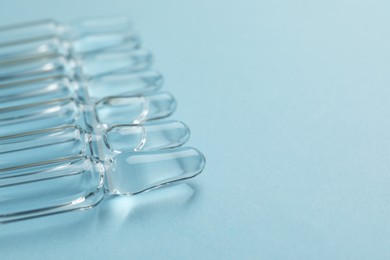 Photo of Many medical ampoules with solution on light blue background, closeup. Space for text