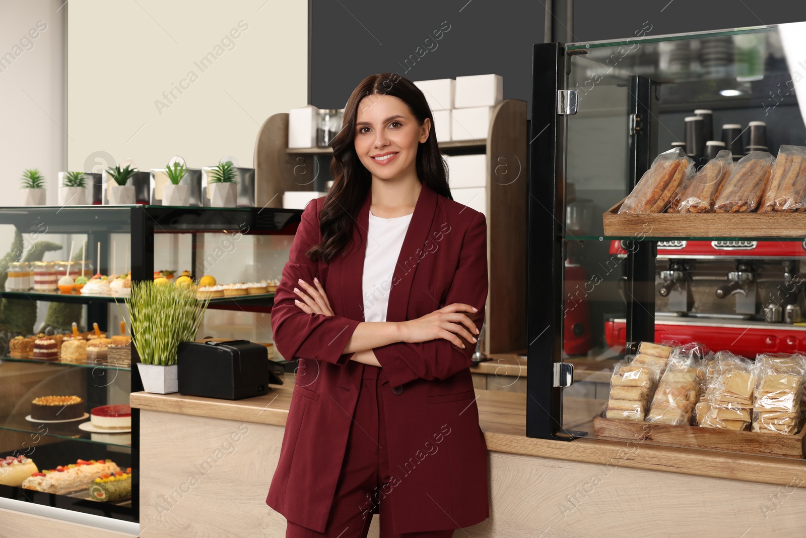 Photo of Portrait of business owner near showcase with pastries in her cafe