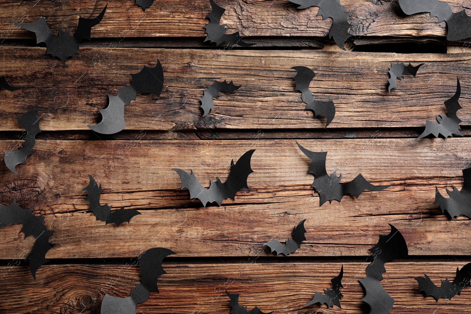 Photo of Paper bats on wooden background, flat lay. Halloween decor