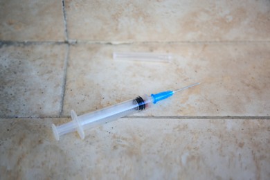 Photo of Empty syringe with needle on tiled surface, closeup