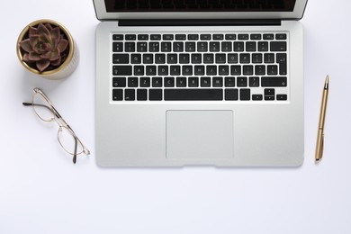 Photo of Modern laptop, houseplant, glasses and pen on white table, flat lay