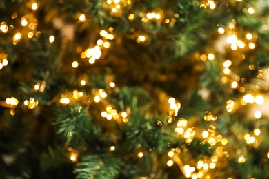 Photo of Blurred view of Christmas tree with bright fairy lights, closeup. Bokeh effect