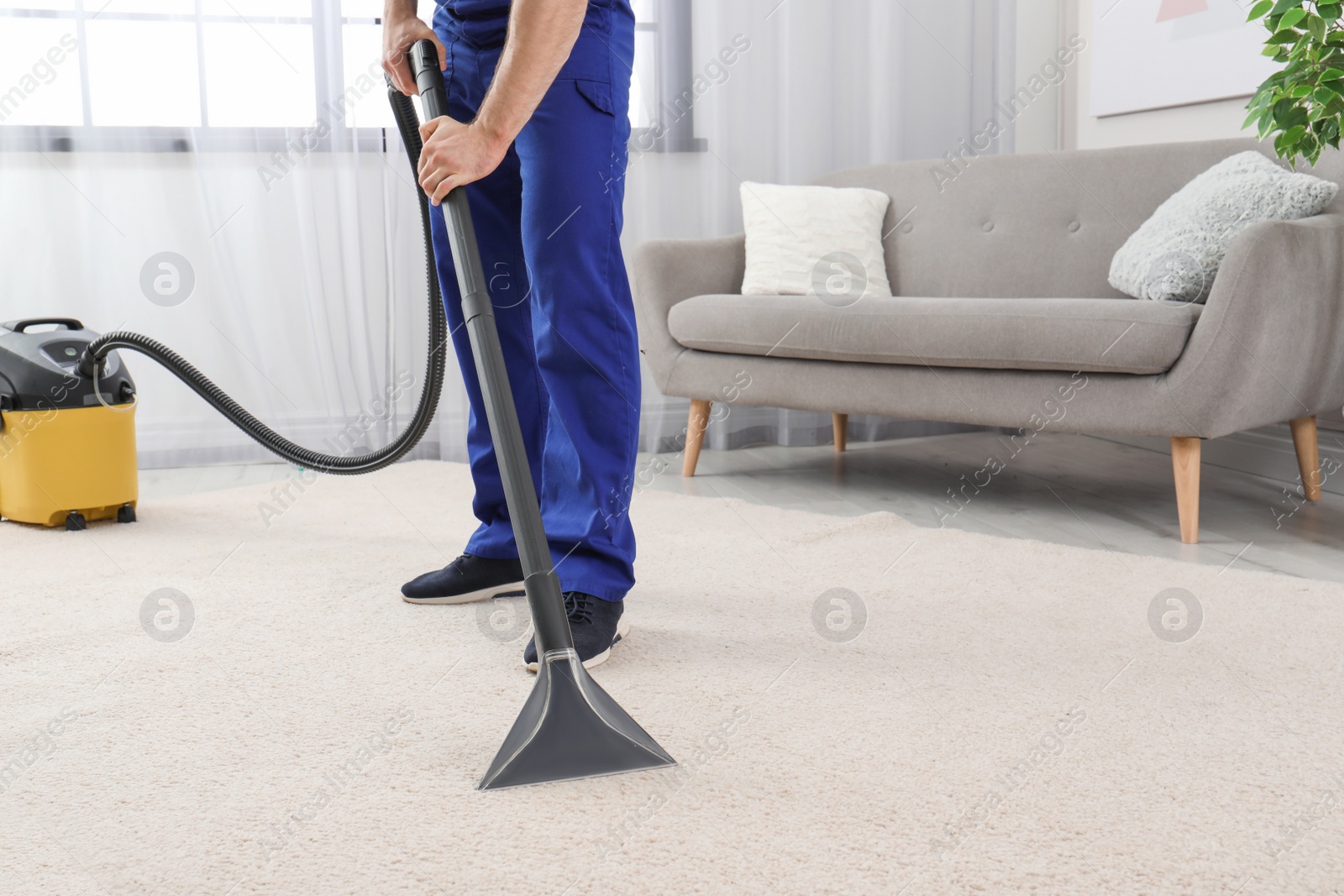 Photo of Man removing dirt from carpet with vacuum cleaner indoors, closeup. Space for text