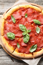 Tasty pepperoni pizza with basil on wooden table, top view