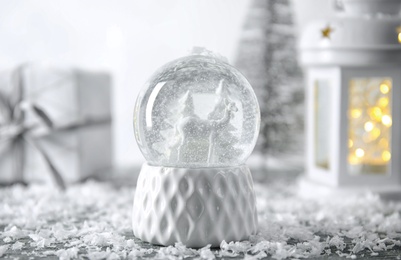 Photo of Snow globe with Christmas decorations on table