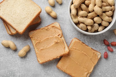 Photo of Tasty peanut butter sandwiches and peanuts on gray table, flat lay