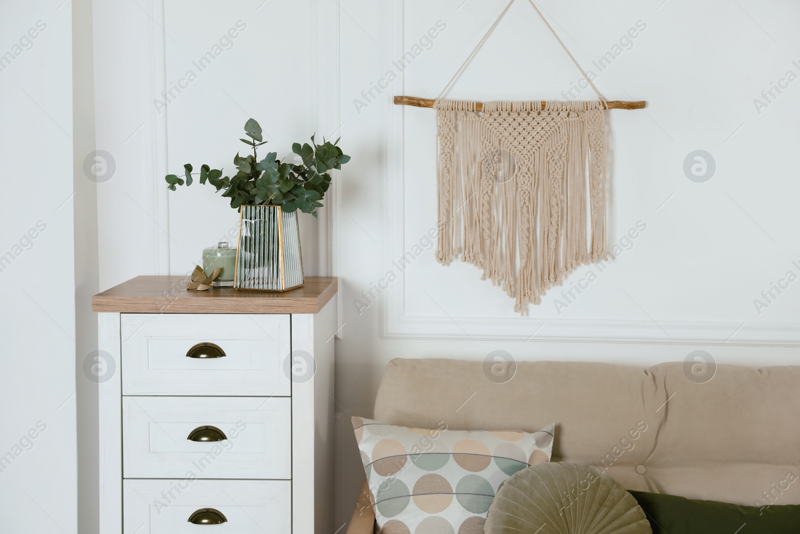 Photo of Stylish living room interior with comfortable sofa, eucalyptus branches and beautiful decor elements