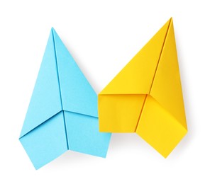 Photo of Handmade light blue and yellow paper planes isolated on white, top view