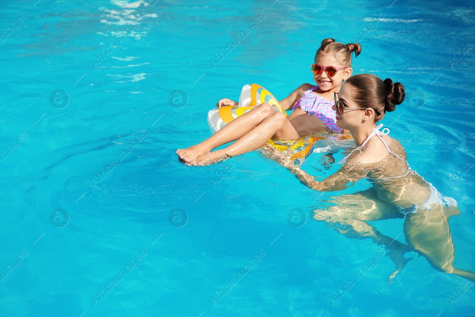 Photo of Young mother with little daughter in swimming pool on sunny day