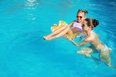 Photo of Young mother with little daughter in swimming pool on sunny day