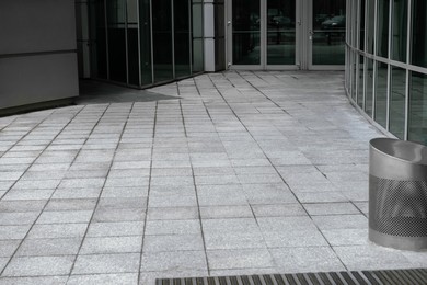Photo of View on grey sidewalk near building. Footpath covering