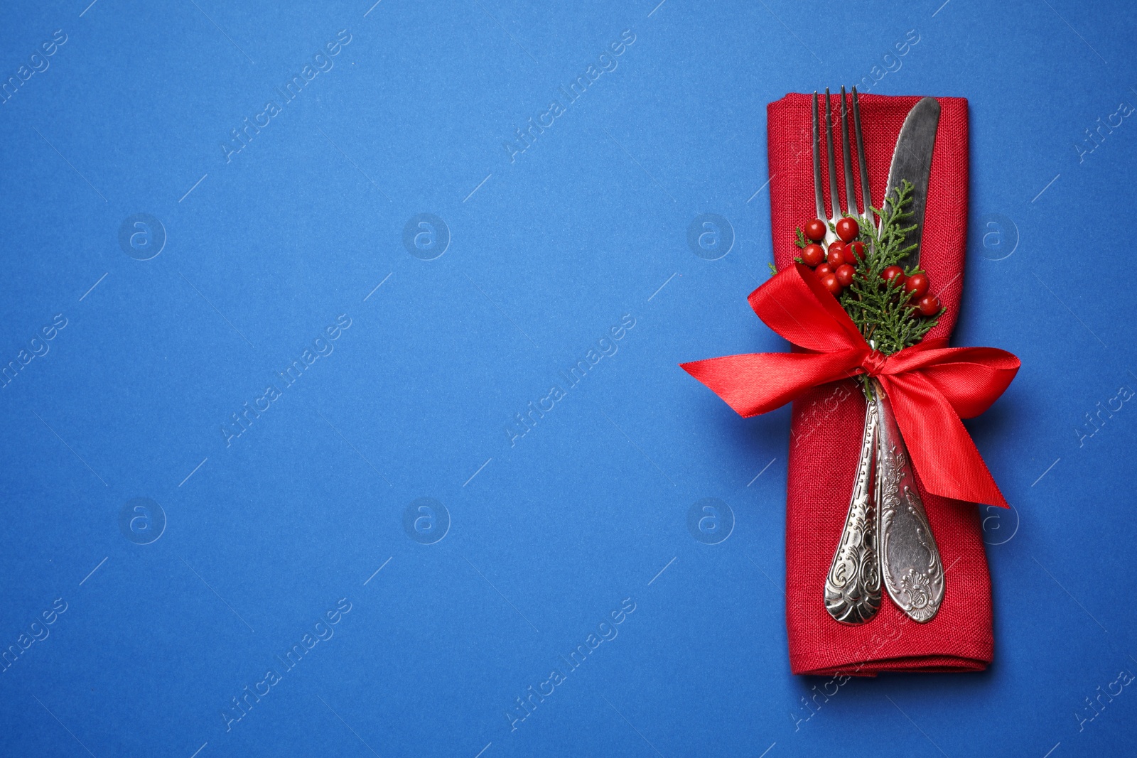 Photo of Cutlery set on blue background, top view with space for text. Christmas celebration