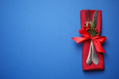 Cutlery set on blue background, top view with space for text. Christmas celebration