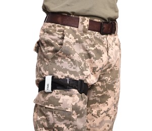 Photo of Soldier in military uniform with medical tourniquet on leg against white background, closeup