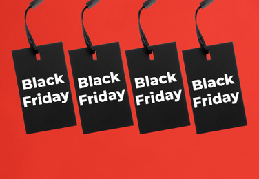 Tags with text BLACK FRIDAY on red background, flat lay 