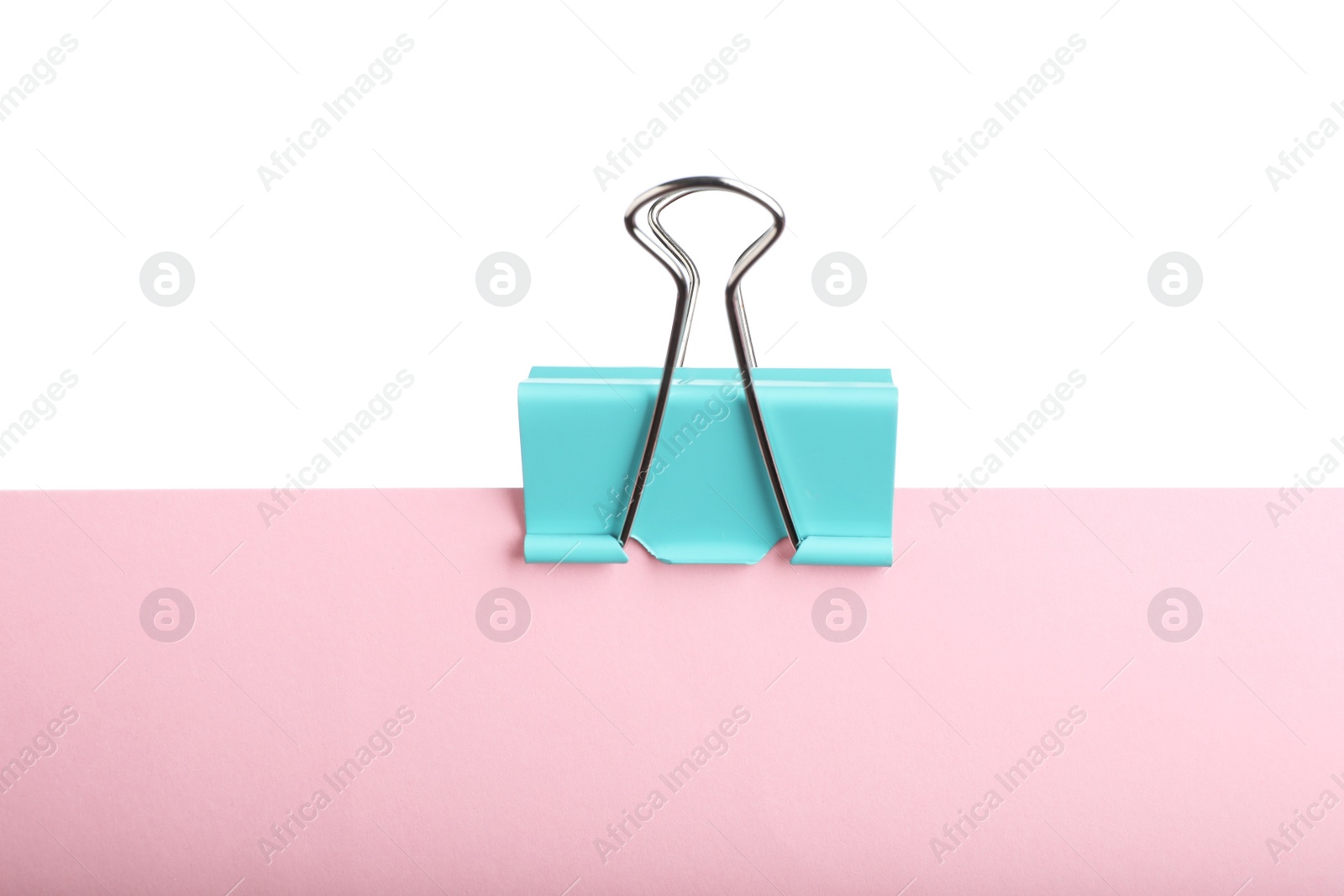 Photo of Pink paper with turquoise binder clip isolated on white