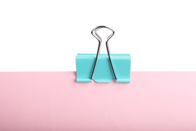 Pink paper with turquoise binder clip isolated on white