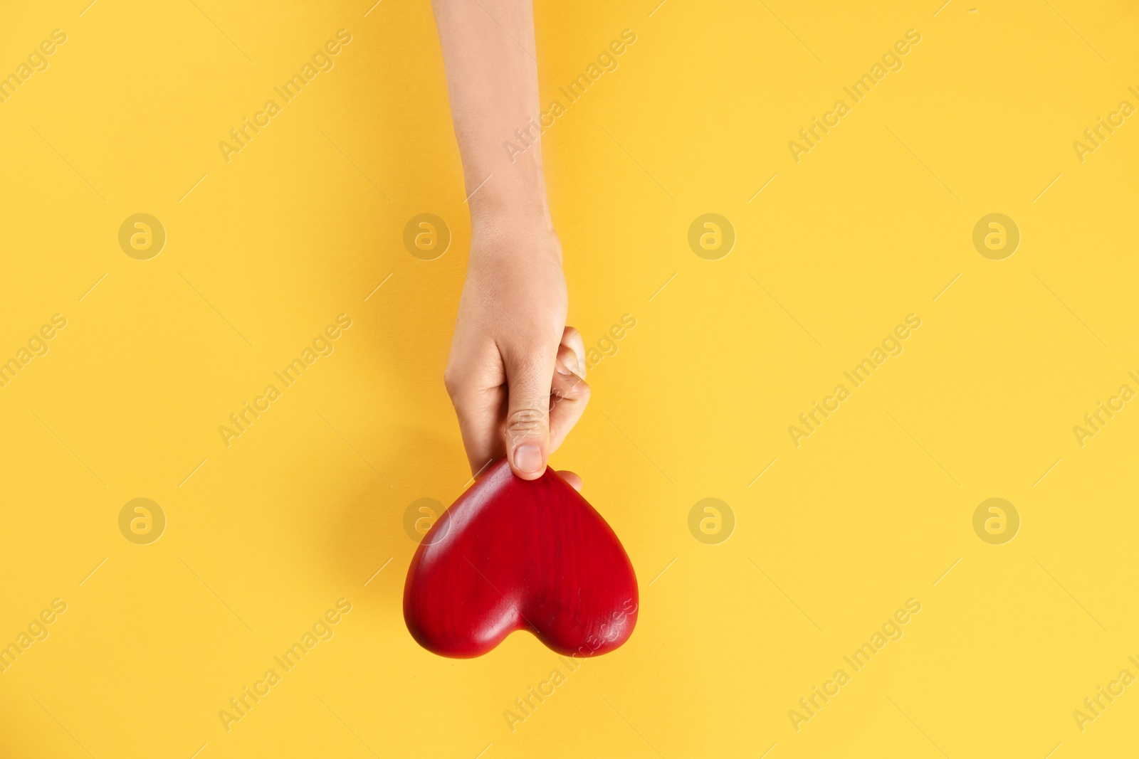 Photo of Woman holding decorative heart on color background, top view