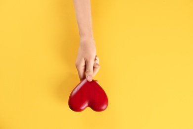 Woman holding decorative heart on color background, top view