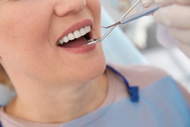 Dentist examining patient's teeth in modern clinic, closeup. Space for text