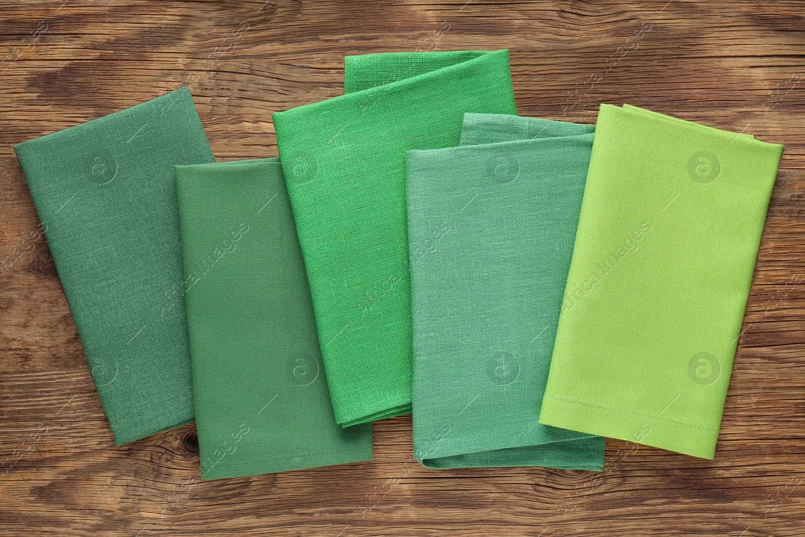 Photo of Different kitchen napkins on wooden table, flat lay