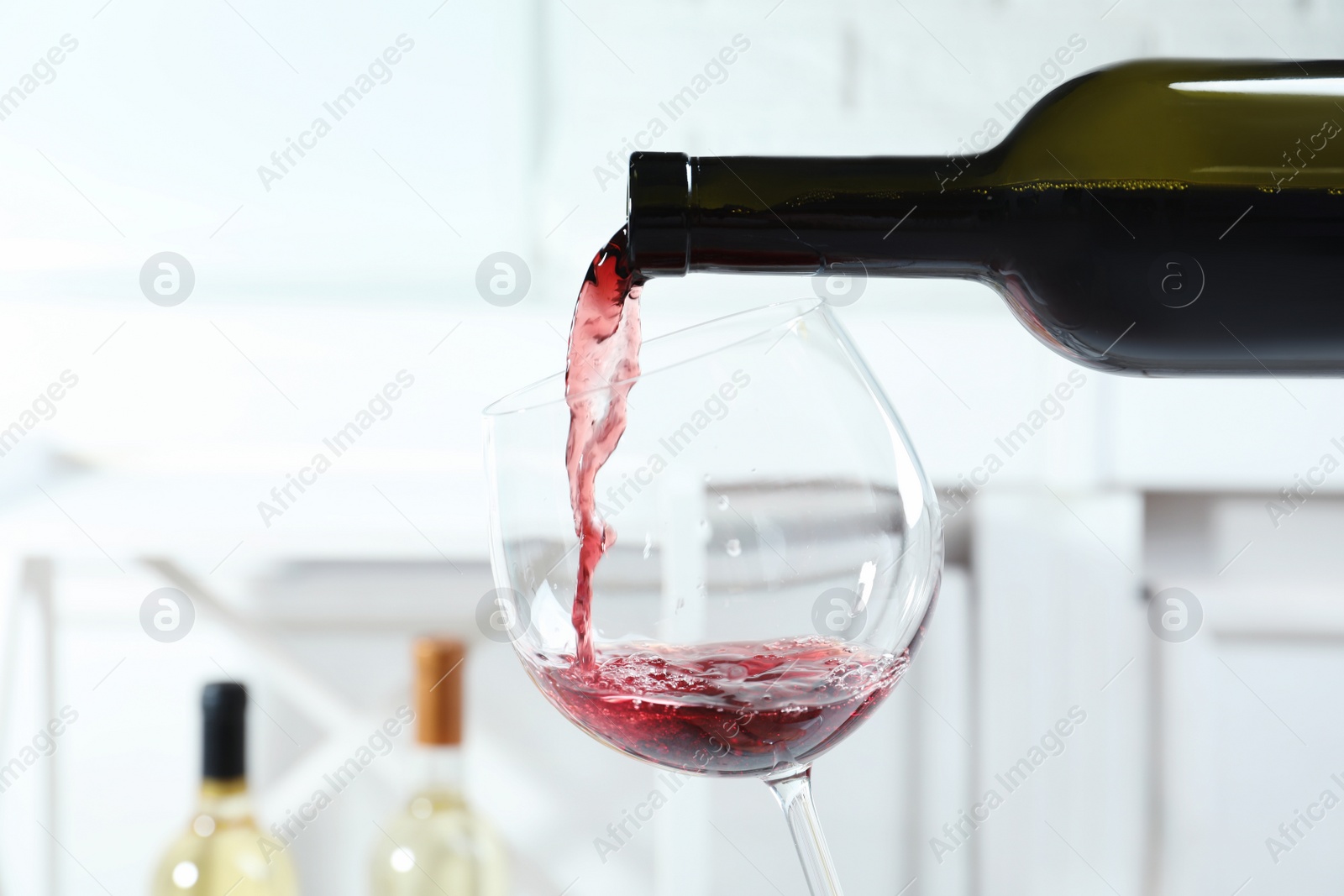 Photo of Pouring delicious red wine into glass on light background