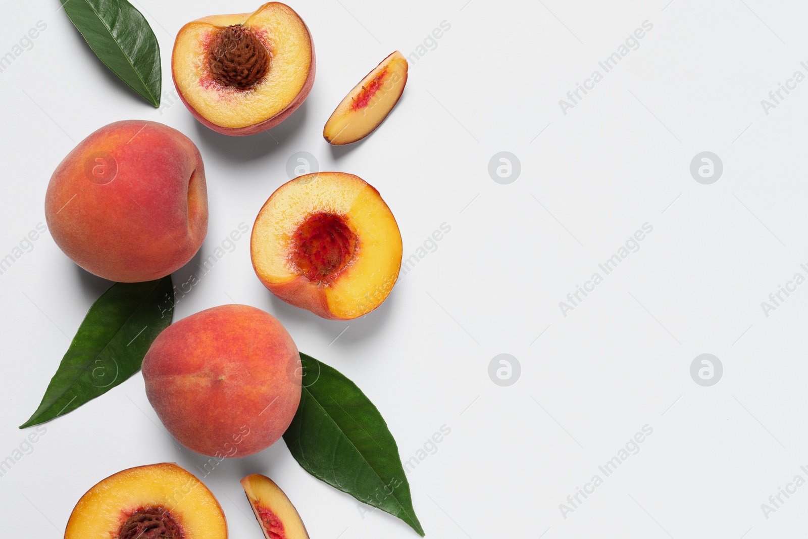 Photo of Cut and whole fresh ripe peaches with green leaves on white background, flat lay. Space for text