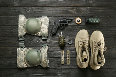 Set of military equipment and combat boots on wooden background, flat lay